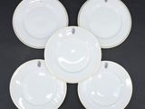 quatre assiettes blanches à bord doré sur fond noir