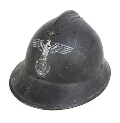 un vieux casque orné d'un oiseau, posé sur une surface blanche