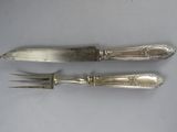 two forks and a knife on a table with a white background