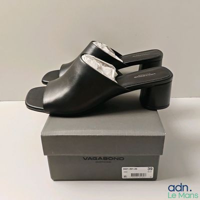 les mules en cuir noir sont posées sur une boîte