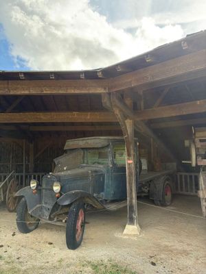 une vieille voiture garée dans un garage, sous une structure en bois