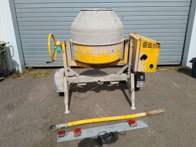 concrete mixer sitting in front of a garage next to a tool box