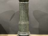 a green vase sitting on top of a wooden table
