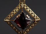 un gros plan d'un pendentif en or serti d'une pierre rouge
