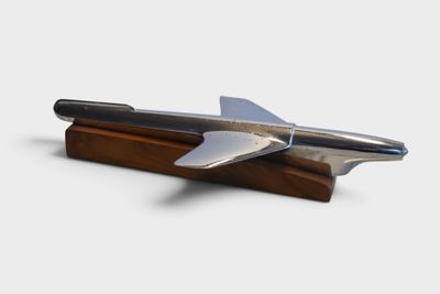a silver airplane on a wooden stand on a white background