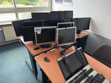 laptops and monitors on a desk in a room with a window