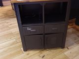 une armoire noire avec un plateau en bois, posée sur un parquet