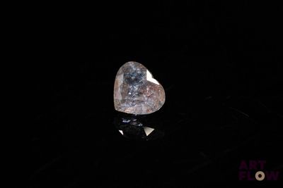 a close up of a heart shaped diamond on a black surface