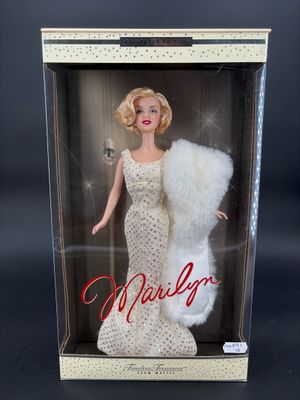 La poupée Barbie se trouve dans une boîte avec une étole en fourrure.