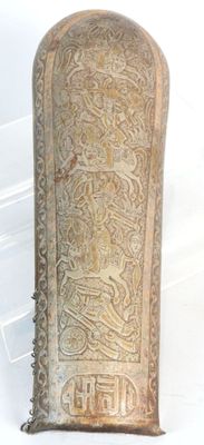 an old metal object with a design on it on a white surface