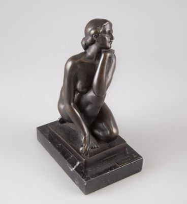 une statue en bronze représentant une femme assise sur un socle en marbre