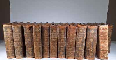 Plusieurs vieux livres sont alignés sur une table blanche