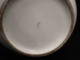 a white vase with a brown rim sitting on a black surface