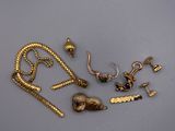quelques bijoux en or sont posés sur une table, à côté d'une paire de ciseaux