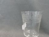 a glass with a white flower on it on a table