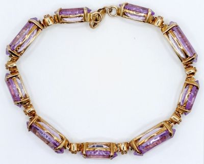 a close up of a purple and gold bracelet on a white surface