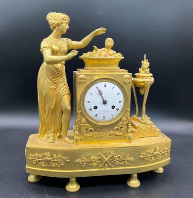 une horloge dorée représentant une femme tenant une bougie