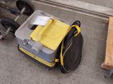 une valise jaune et noire posée par terre à côté d'un chariot