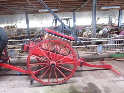 une calèche rouge tirée par des chevaux, garée dans une grange