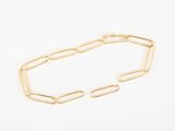 a close up of a gold chain bracelet on a white surface
