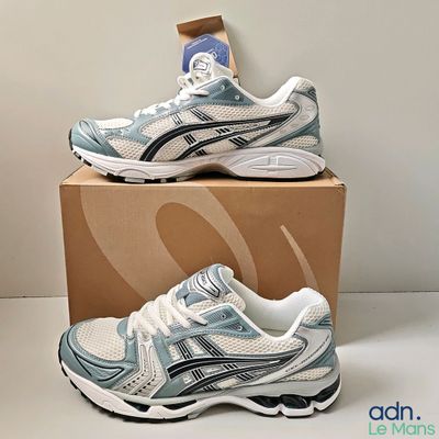 two pairs of asics running shoes are on a cardboard box