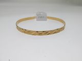 gros plan d'un bracelet en or sur une surface blanche