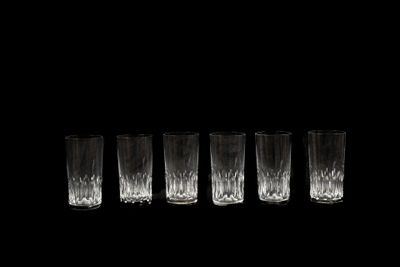 six verres sont alignés sur un fond noir