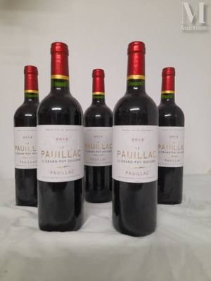 four bottles of red wine are lined up on a table