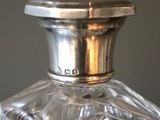 a glass bottle with a silver top sitting on a table
