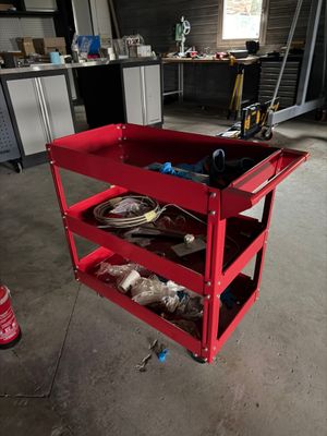 a red work cart with tools on it in a garage