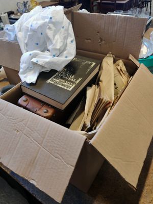une boîte en carton remplie de livres et de papiers, posée par terre