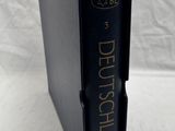an old black book with german writing on it sitting on a white surface