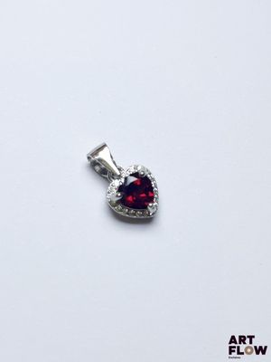un gros plan d'un pendentif rouge en forme de cœur posé sur une surface blanche