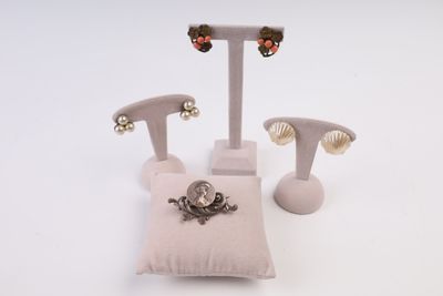 trois paires de boucles d'oreilles et un oreiller posés sur une surface blanche