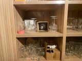 bottles and glasses on a shelf in a room with wood paneling