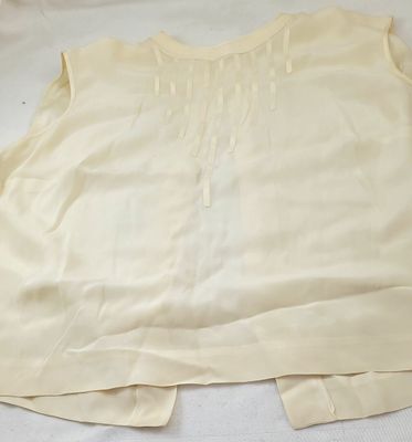 Le haut d'une chemise blanche est posé sur une surface blanche.
