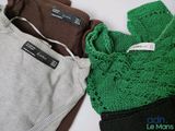 three pairs of sweaters with labels on them sitting on a table