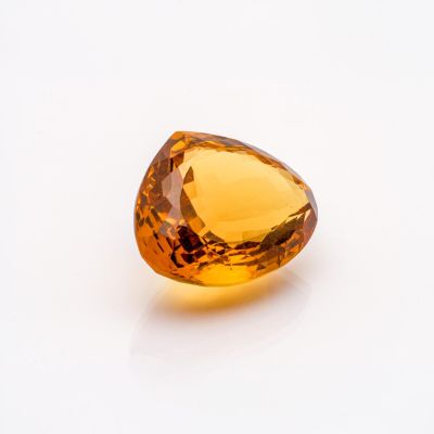 an orange sapphire stone on a white surface