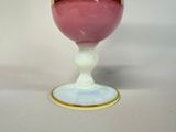 a pink glass with a gold rim sitting on a white table