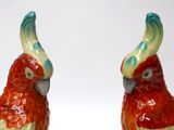 two red and green birds sitting on a white surface