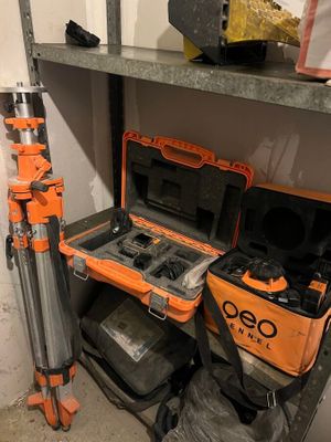 une mallette à outils orange posée sur une étagère, à côté d'un trépied