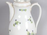 a white coffee pot with blue and green flowers on it