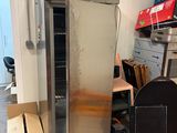 a silver refrigerator in the middle of a room with boxes on the floor
