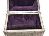 an old silver box with purple velvet lining on a white surface