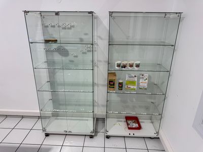 two glass shelves with various items in them on the floor