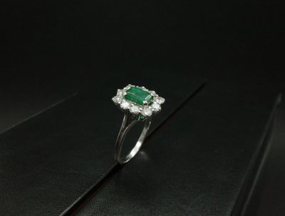 une bague en émeraude et diamant sur une surface noire