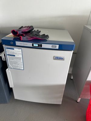 un réfrigérateur blanc sur lequel sont posés des gants, à côté d'une chaise rouge