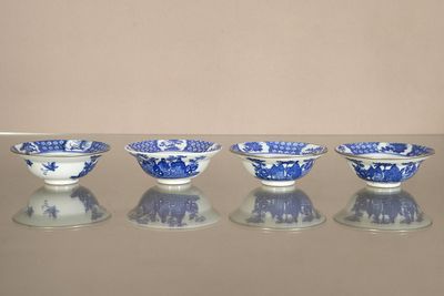 four blue and white bowls are lined up on a glass table
