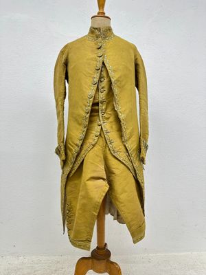 a yellow coat on a mannequin stand with a white wall in the background