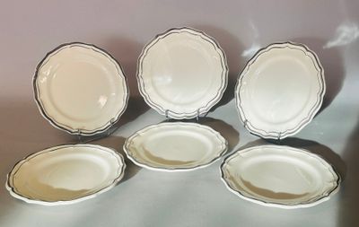 six assiettes blanches à bordure argentée sont disposées sur une table